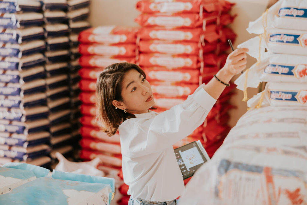 As an FSVP importer, a woman carefully logs her rice imports for future evaluation to assure continued FSVP compliance.