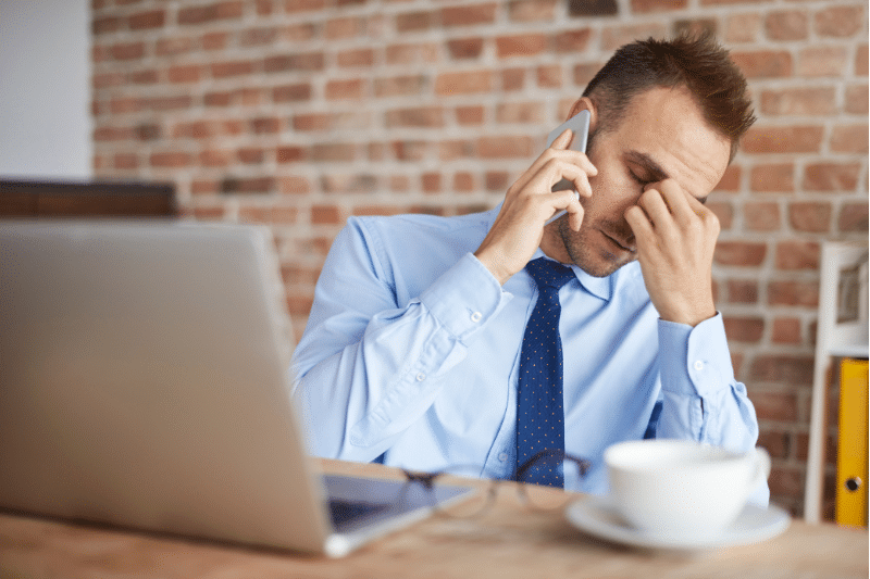 A businessman stressfuly works through a registration cancellation on the phone.