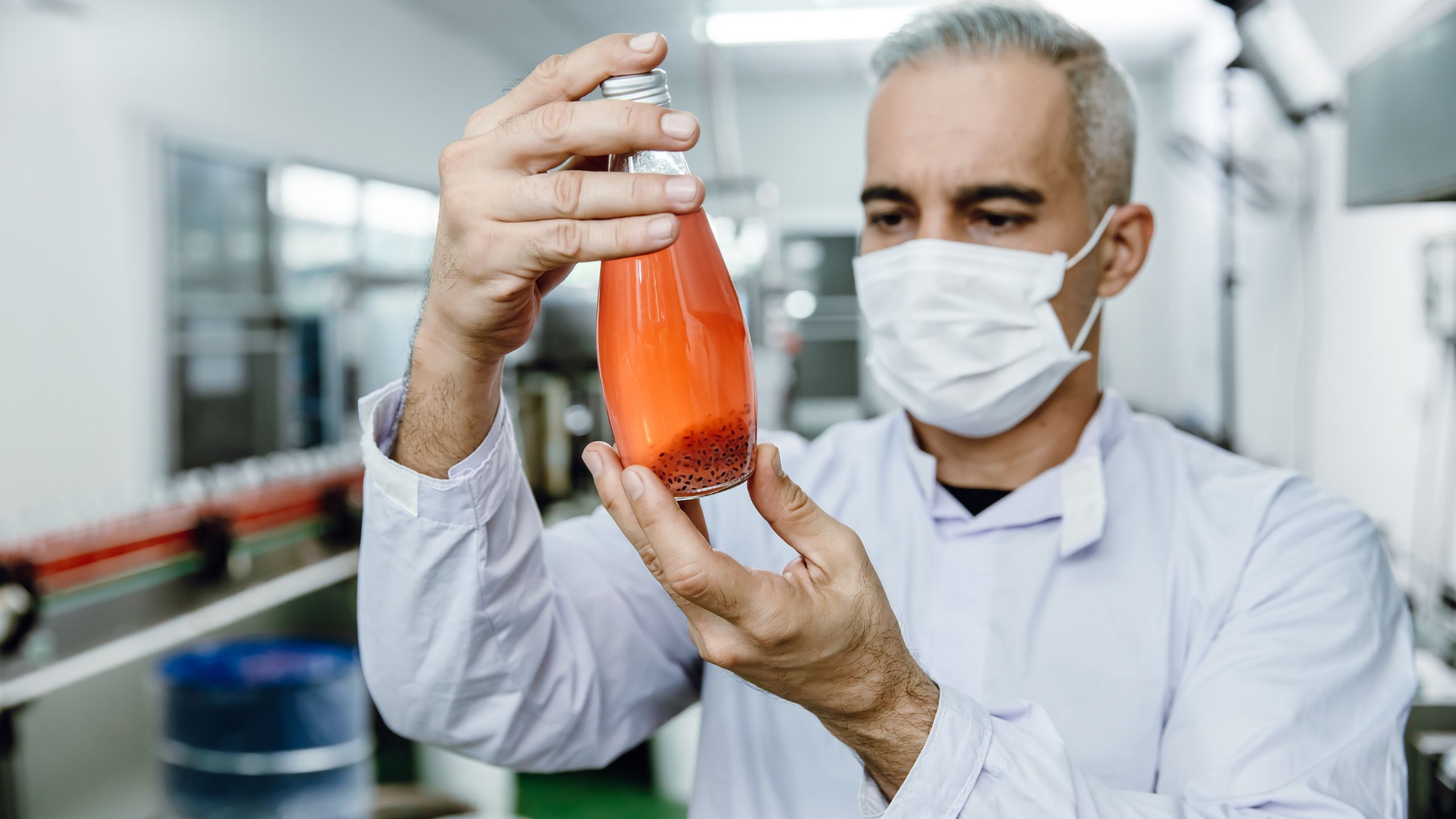 An SQF Practitioner examine a beverage product according to SQF & FDA Food Defense.